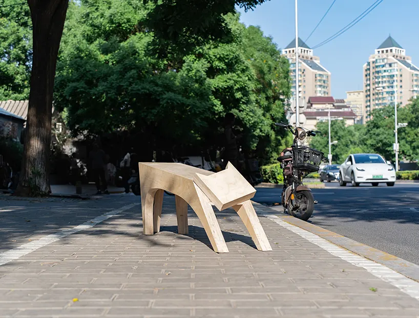 ม้านั่งไม้ The Stretching Cat Bench รูปทรงคล้ายแมวกำลังยืดตัว ตั้งอยู่บนพื้นเรียบ