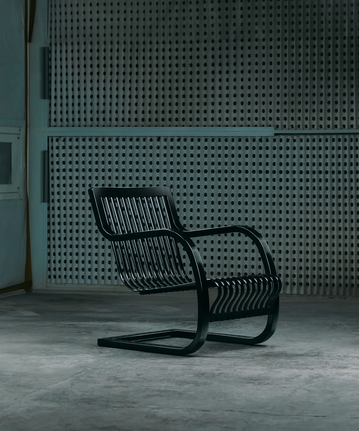 Bamboo Chair สีดำเงาวางในห้องโล่งพื้นปูน แสงสลัว