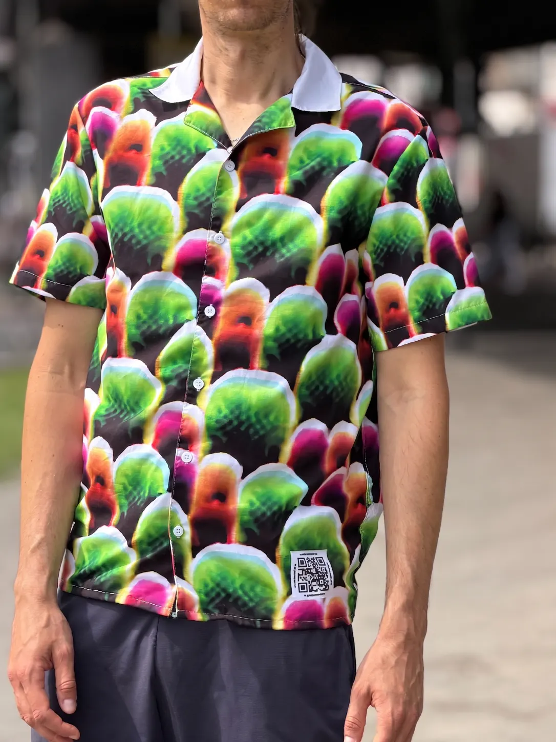 ภาพระยะใกล้ของเสื้อ Digital Camouflage ลายก้อนสีเขียว ชมพู ส้ม เรียงซ้อนกันบนพื้นดำ