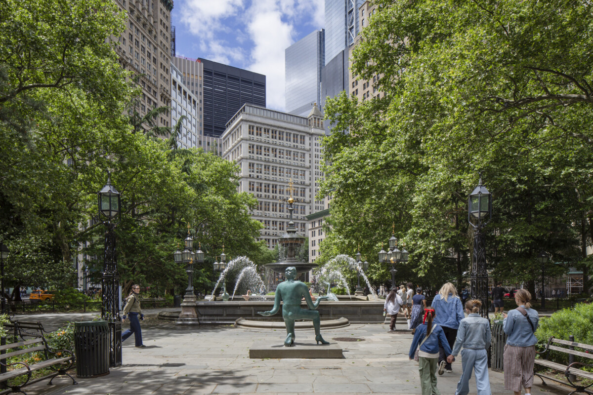 มุมกว้างของ City Hall Park ที่มีประติมากรรมตั้งอยู่ท่ามกลางคนเดินผ่าน
