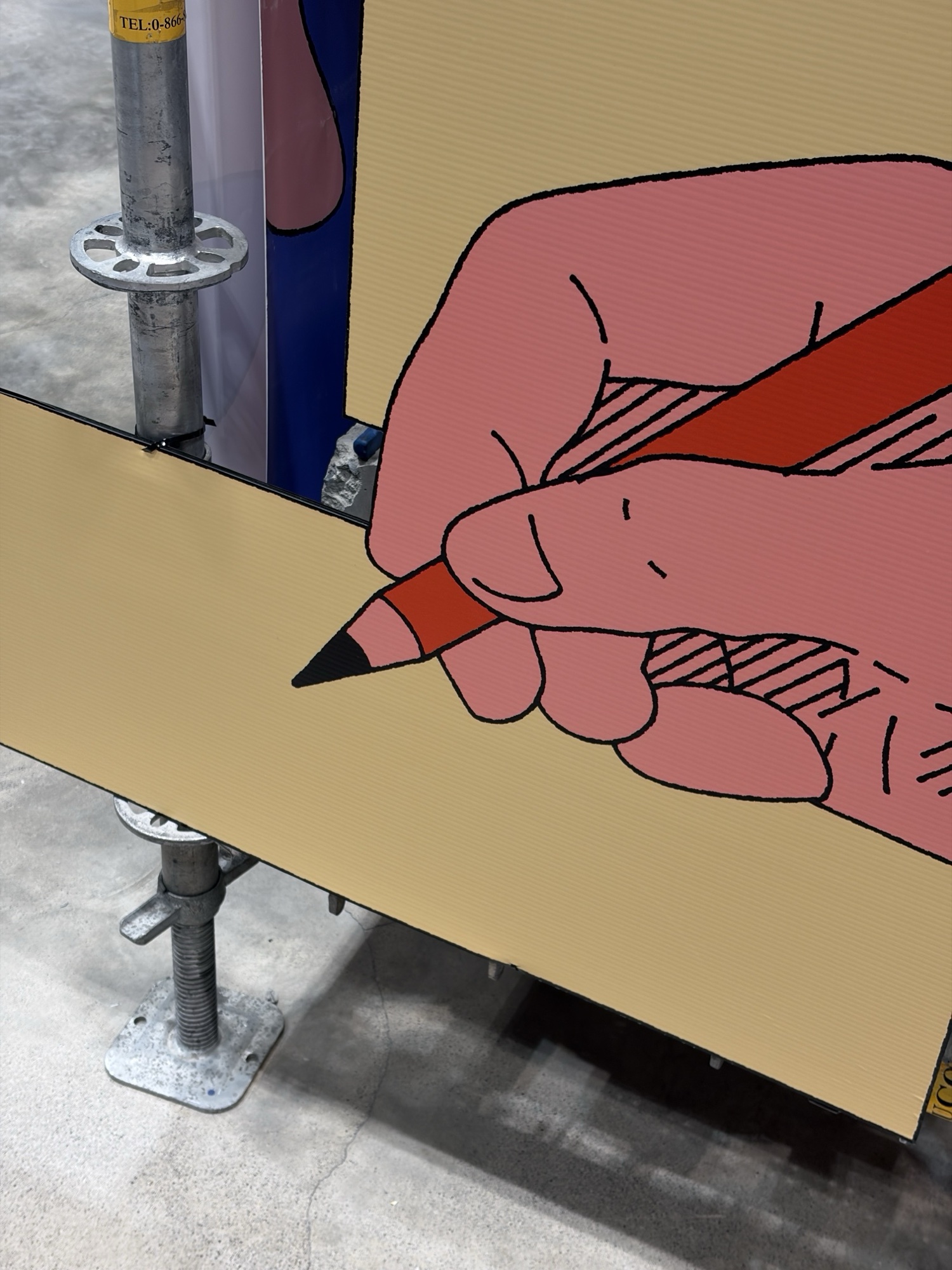ภาพมือสีชมพูจับดินสอสีแดงบนแผ่นป้าย ยึดกับนั่งร้านเหล็ก