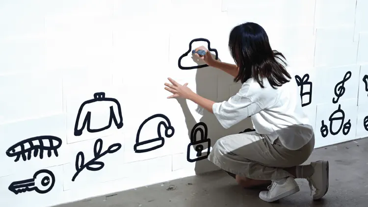 ผู้ชมเติมภาพวาดเส้นดำบนผนังขาวในงานดูเดิลส์