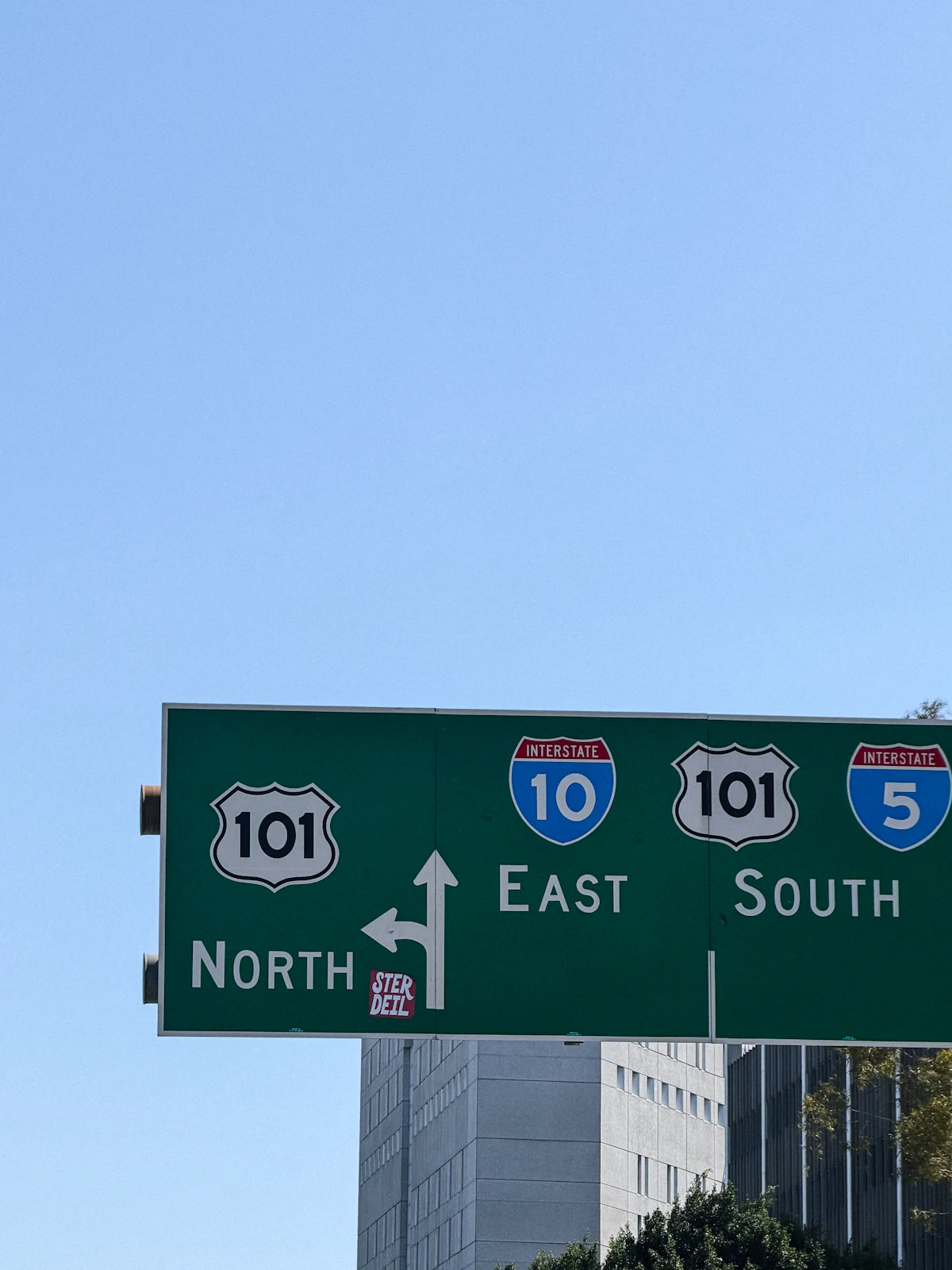 ป้ายทางหลวงสีเขียวแสดงเส้นทาง 101 East และ Interstate 10 กับ 5 บนท้องฟ้าสีฟ้า