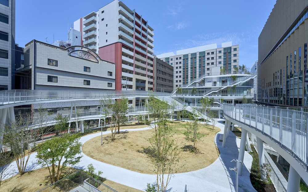 ทางเดินยกระดับพาดผ่านระหว่างอาคารร้านค้ากับอาคารรอบข้างของ Meiji Park