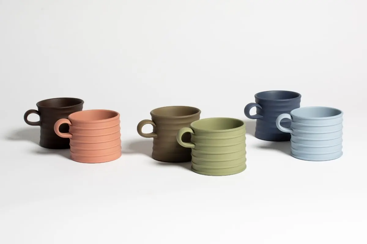 แก้วมัคหกใบจากคอลเลกชัน JW Anderson x Wedgwood วางเรียงกันเป็นคู่สี น้ำตาลเข้ม ส้มดินเผา น้ำตาลอมเขียว เขียวอ่อน น้ำเงินเข้ม และฟ้าอ่อน