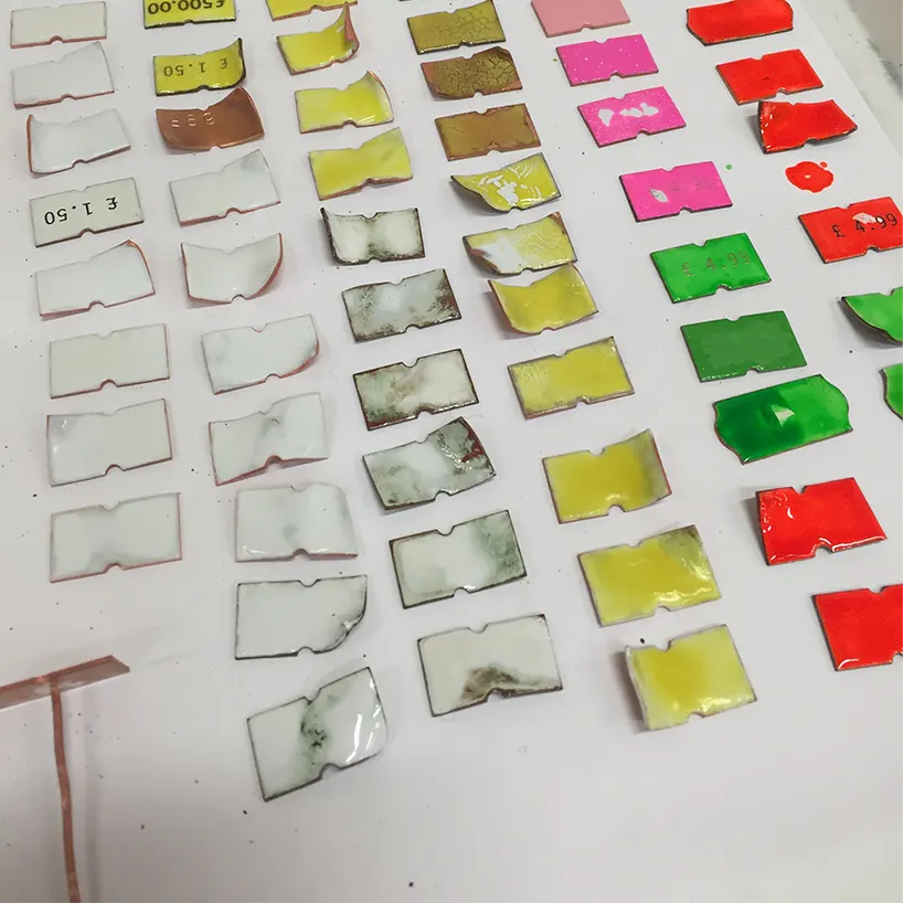 เข็มกลัดทองแดงลงยาหลายชิ้นวางเรียงกัน สีต่างกันในแต่ละชิ้น