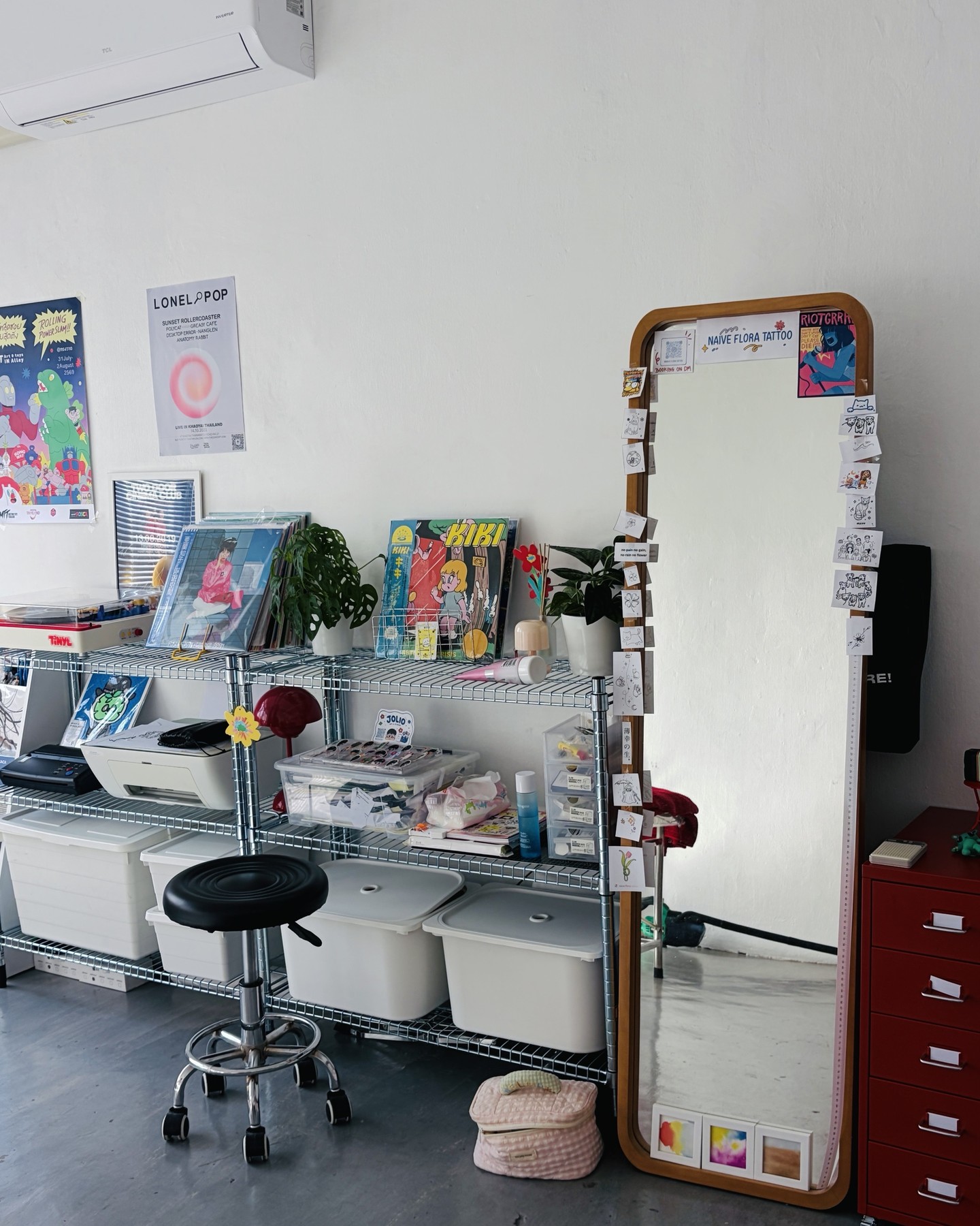กระจกบานยาวที่ติดลายแฟลชของ Naive Flora Tattoo ข้างชั้นเหล็กและตู้ลิ้นชักสีแดง