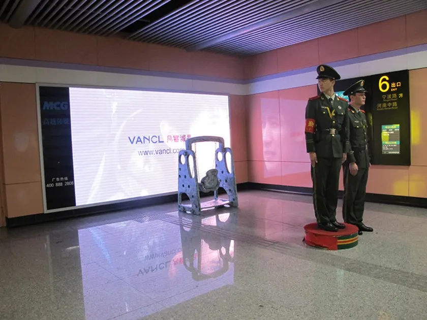 ชิงช้าเด็กตั้งอยู่กลางโถงสถานีรถไฟใต้ดิน โดยมีทหารยามสองนายยืนตรงอยู่บนแท่นด้านขวา