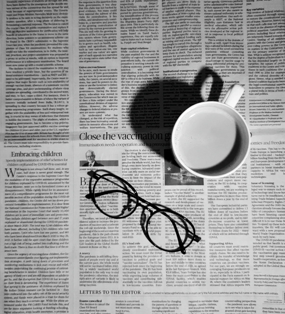 หนังสือพิมพ์วางคู่แว่นตาและกาแฟบนโต๊ะยามเช้า