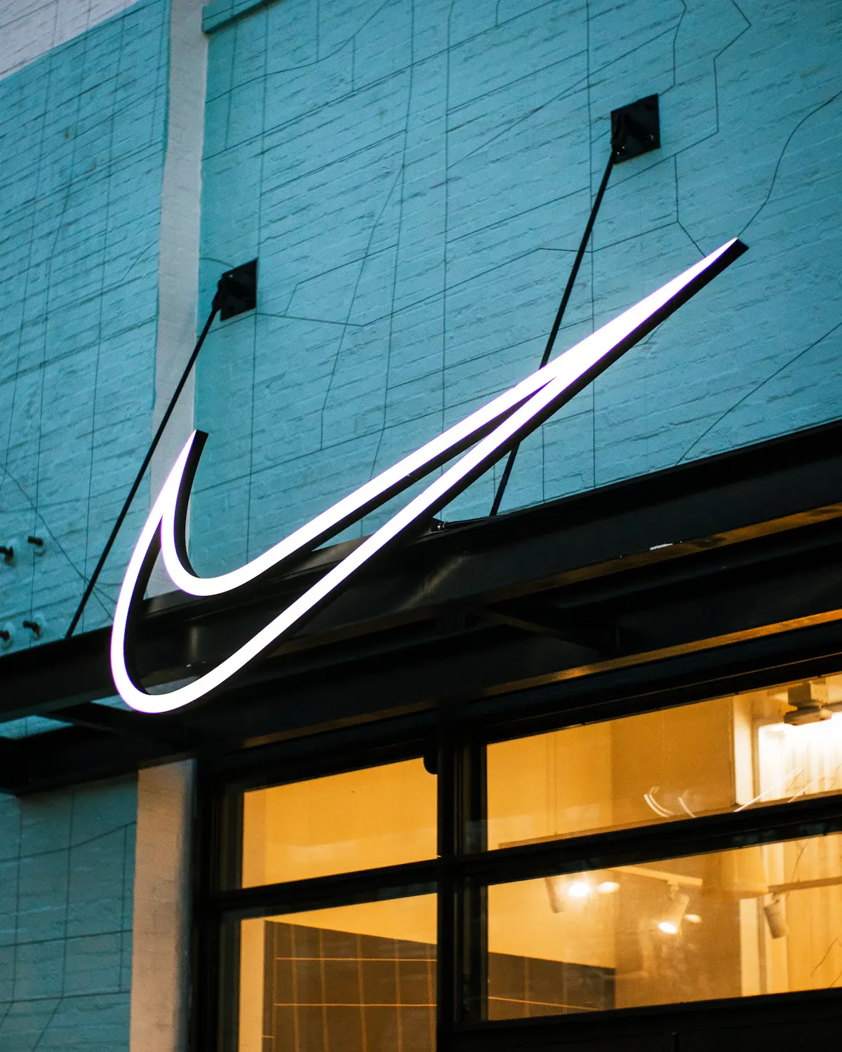 ป้ายนีออน swoosh ของ Nike บนอาคารริมถนน โลโก้ที่อ่านออกแม้ไม่มีชื่อแบรนด์
