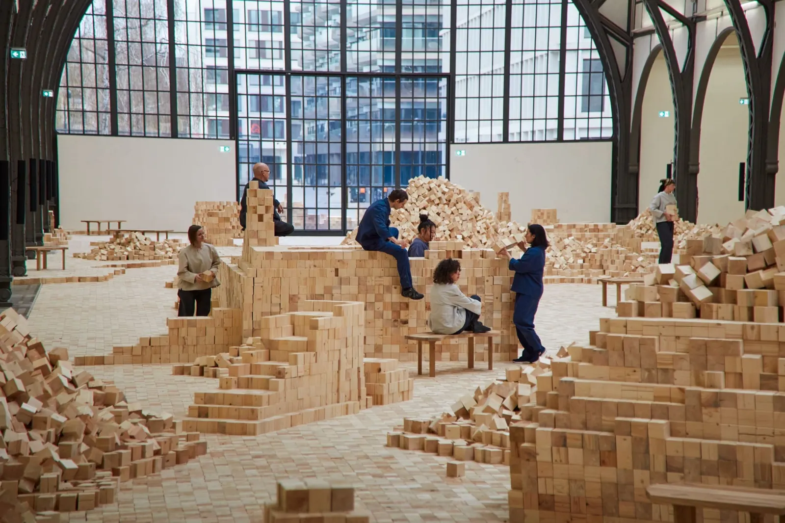 ผู้คนร่วมสร้างโครงสร้างจากก้อนไม้ใน installation ของ Lina Lapelytė