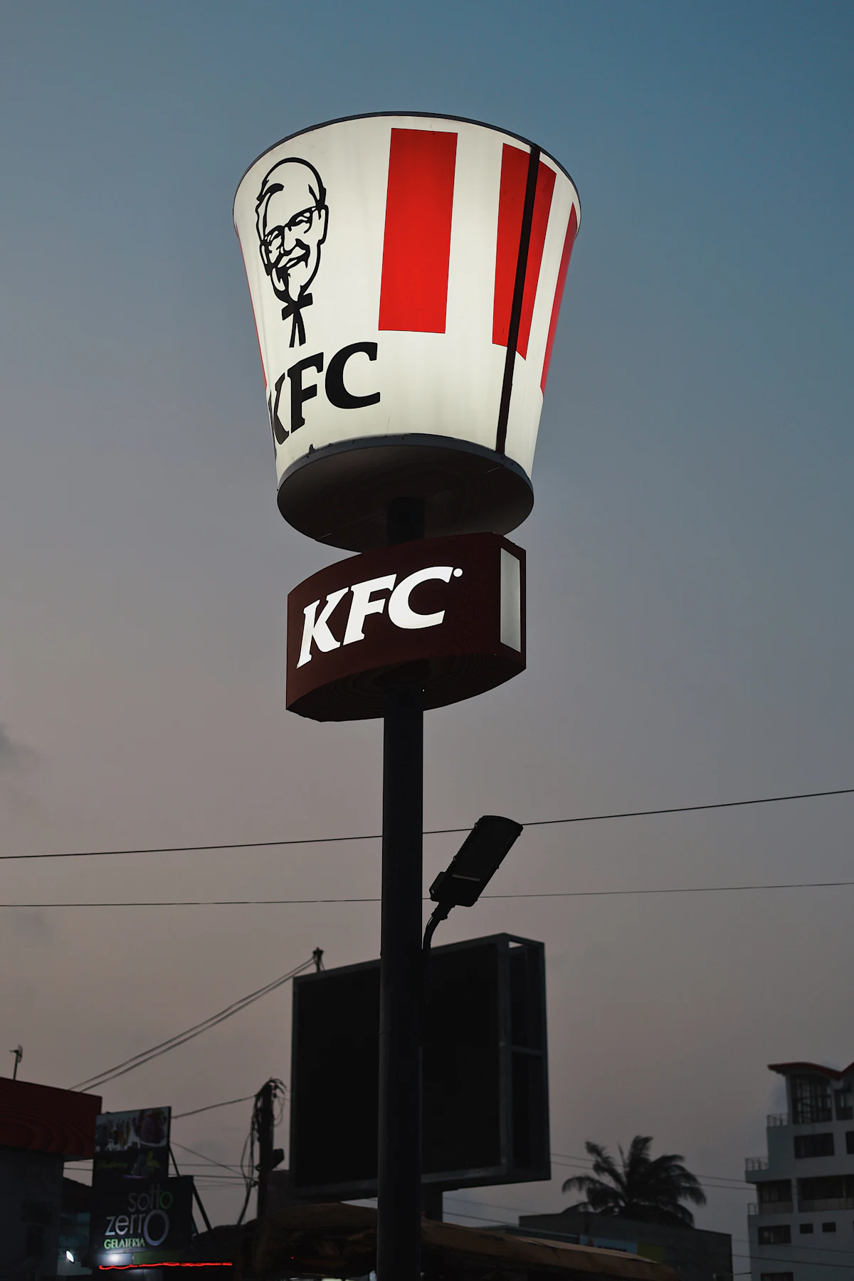 ป้าย KFC ที่มีภาพใบหน้าผู้พันแซนเดอร์สเป็นสัญลักษณ์ของแบรนด์