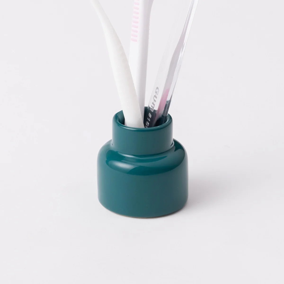 TINYVASE สีเขียวผิวเคลือบด้านวางคู่กับแปรงสีฟัน