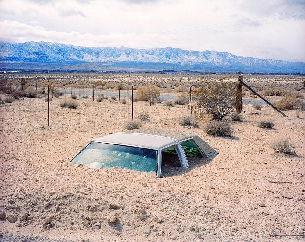รถยนต์ครึ่งคันฝังอยู่ในทรายทะเลทราย Lucerne Valley แคลิฟอร์เนีย ภาพโดย Rob Hann